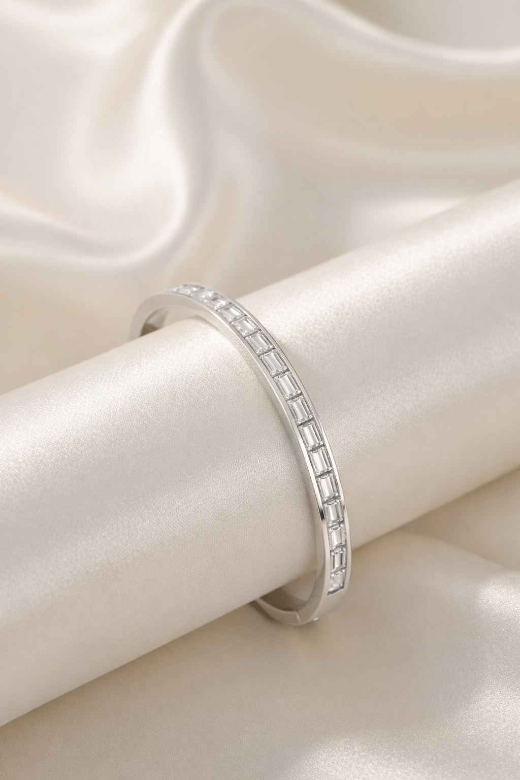 Silver slim bangle bracelet with baguette-cut cubic zirconia stones on satin background