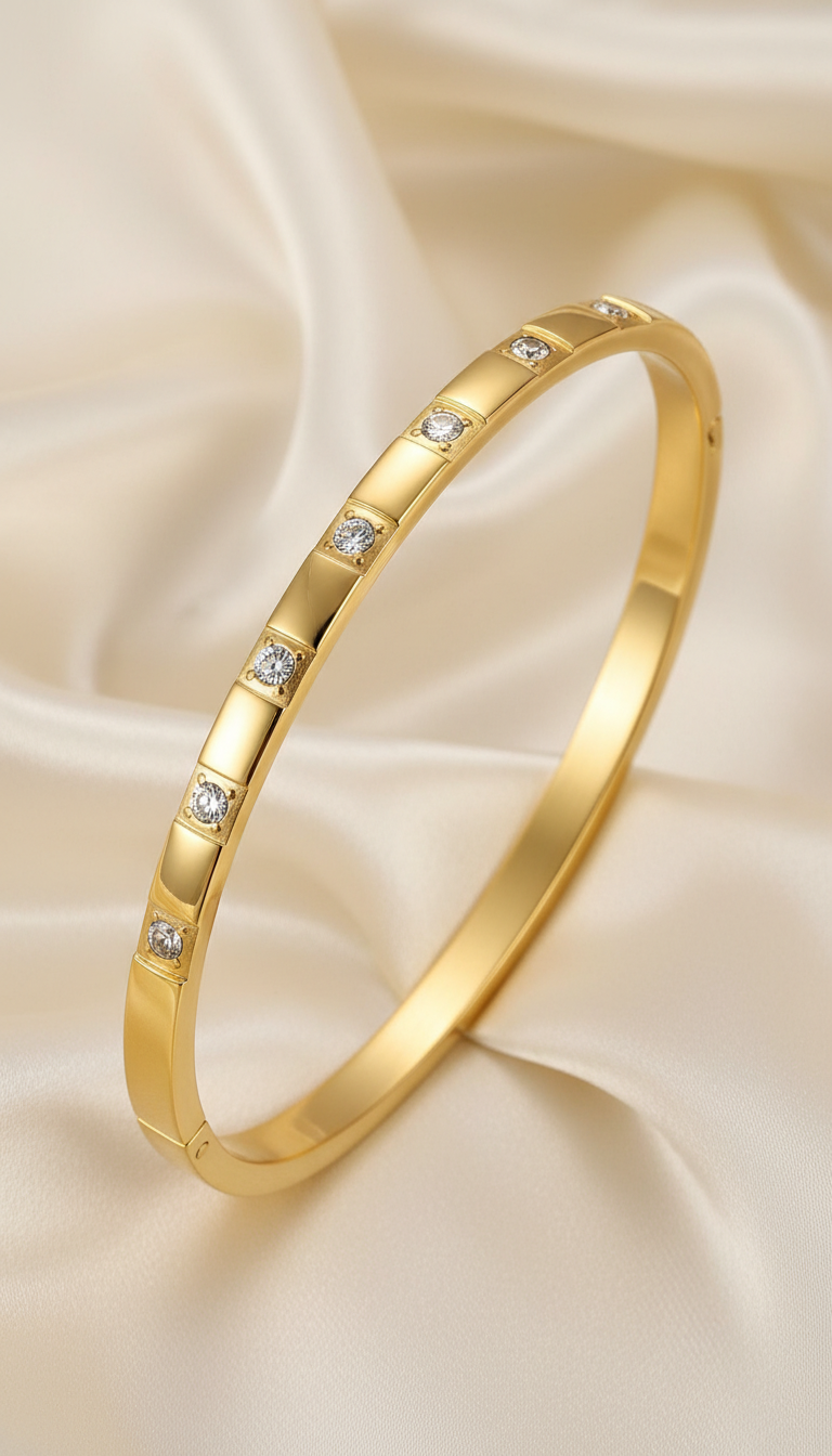 Gold slim bangle bracelet with evenly spaced round cubic zirconia stones on satin background