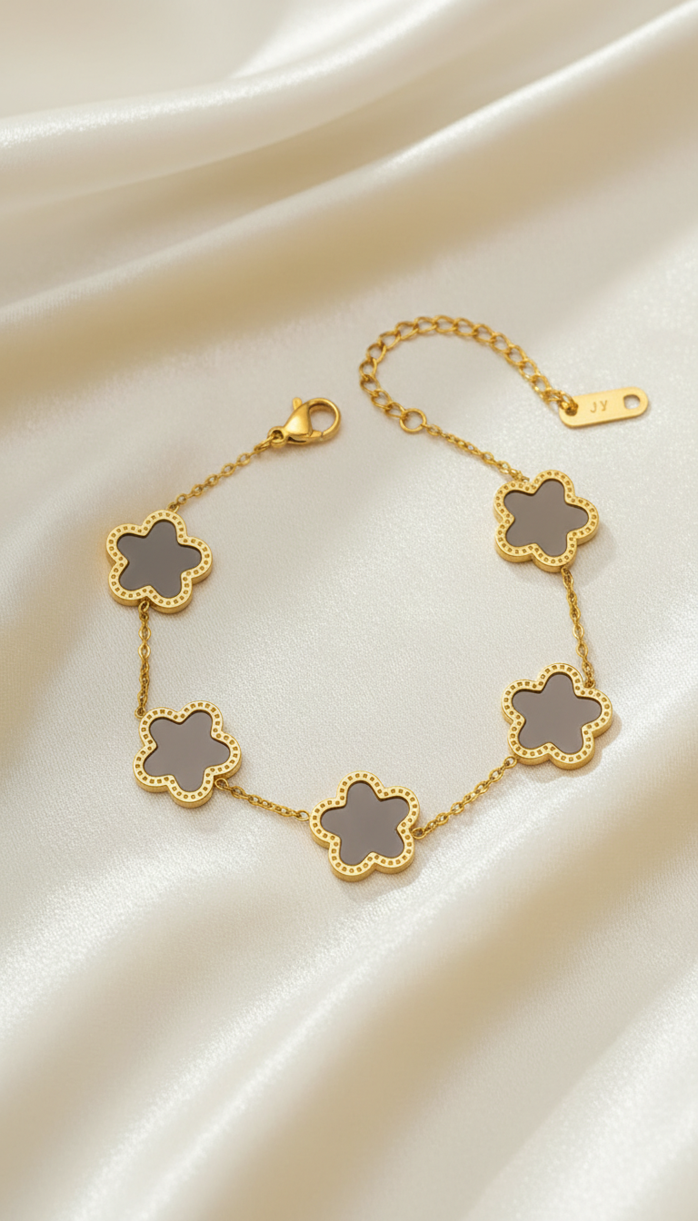 Gold bracelet with five taupe enamel clover charms on satin background