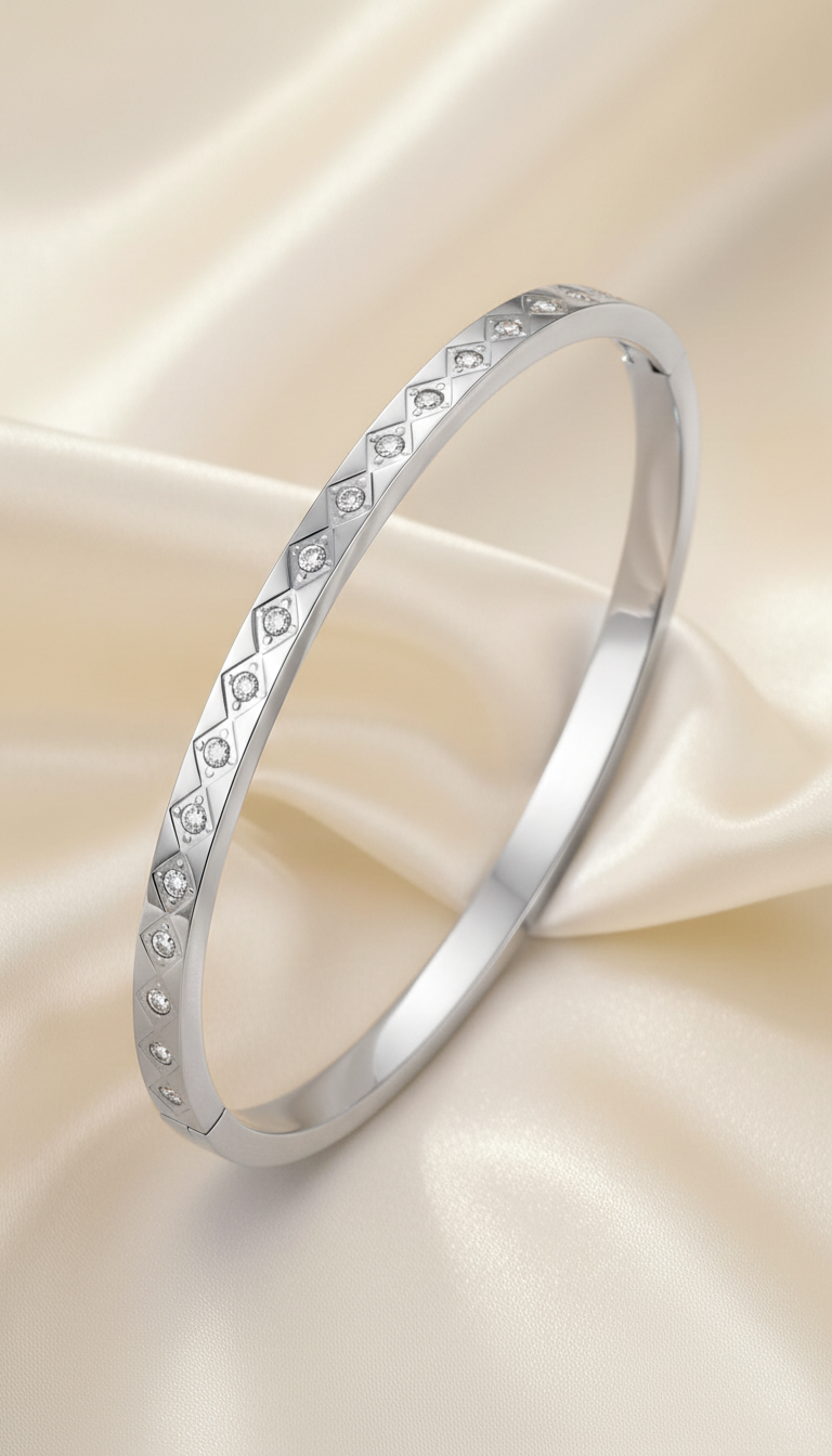 Silver bangle bracelet with engraved diamond grid pattern and cubic zirconia stones on satin background