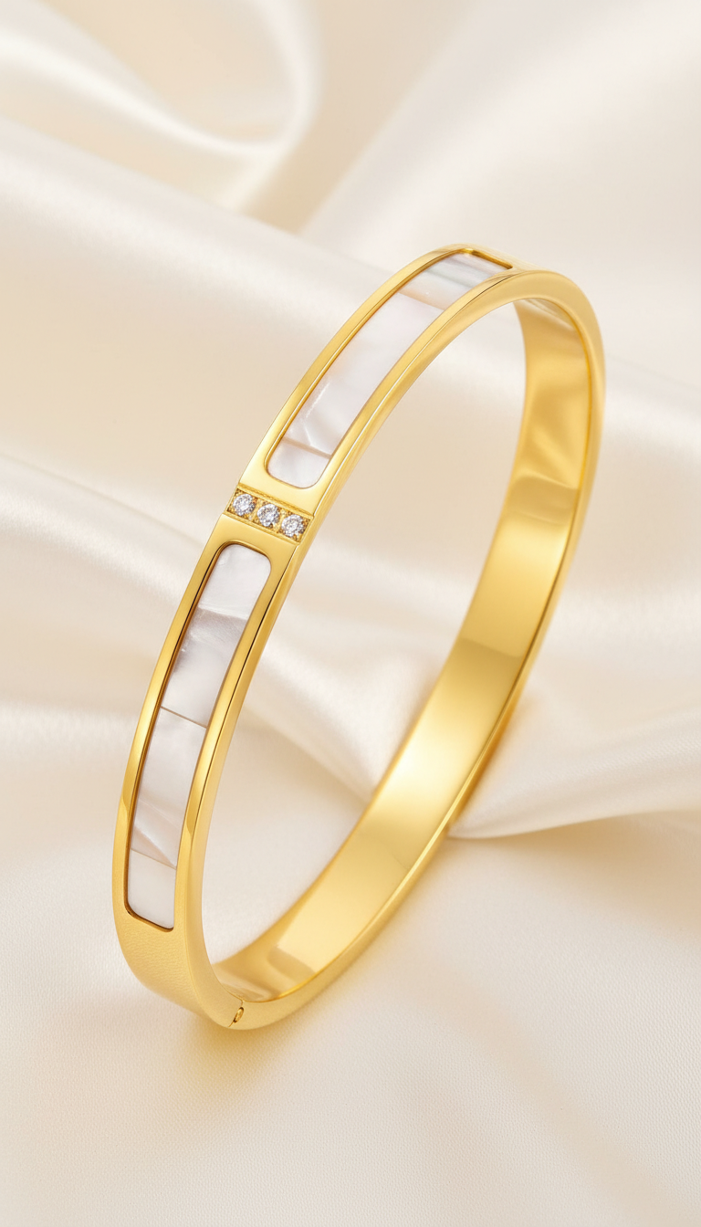 Description Discover the Stainless Steel 18K Gold Plated Crystal Frame Bangle — a beautifully crafted piece of non-tarnish, waterproof jewelry designed for everyday elegance. Featuring smooth white enamel inlay panels framed in polished gold and accented with three precision-set cubic zirconia stones, this bangle blends modern minimalism with subtle sparkle. Key Features Material: Premium stainless steel with 18K gold PVD plating Finish: Non-tarnish and waterproof for lasting shine Design: White enamel inlay with triple cubic zirconia accent Size: (add diameter in cm/inches) Hypoallergenic: Gentle on skin suitable for everyday use Style: Modern chic — perfect for statement styling or stacking Why You’ll Love It Crafted with high-quality gold plating and durable stainless steel, this bangle delivers luxury design with everyday resilience. Its waterproof and non-tarnish finish ensures long-lasting brilliance — ideal for women who appreciate clean lines with a touch of sparkle. Perfect For Everyday wear Office and formal styling Minimal statement looks Gift for her (Anniversary, Birthday, Valentine’s Day, Mother’s Day) Care Instructions To keep your bangle radiant: Avoid contact with perfumes, lotions, and harsh chemicals Remove before swimming or bathing Store in a dry place after use