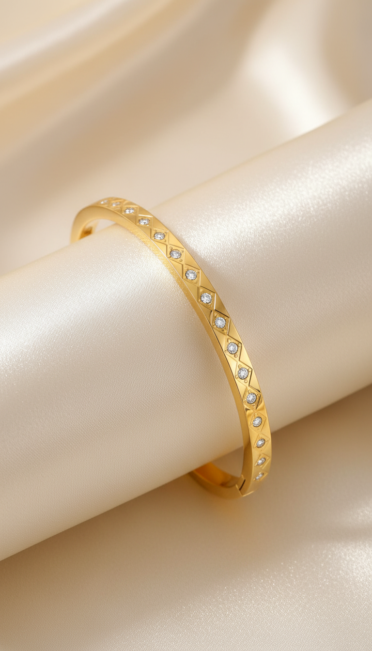 Gold bangle bracelet with engraved diamond grid pattern and cubic zirconia stones on satin background