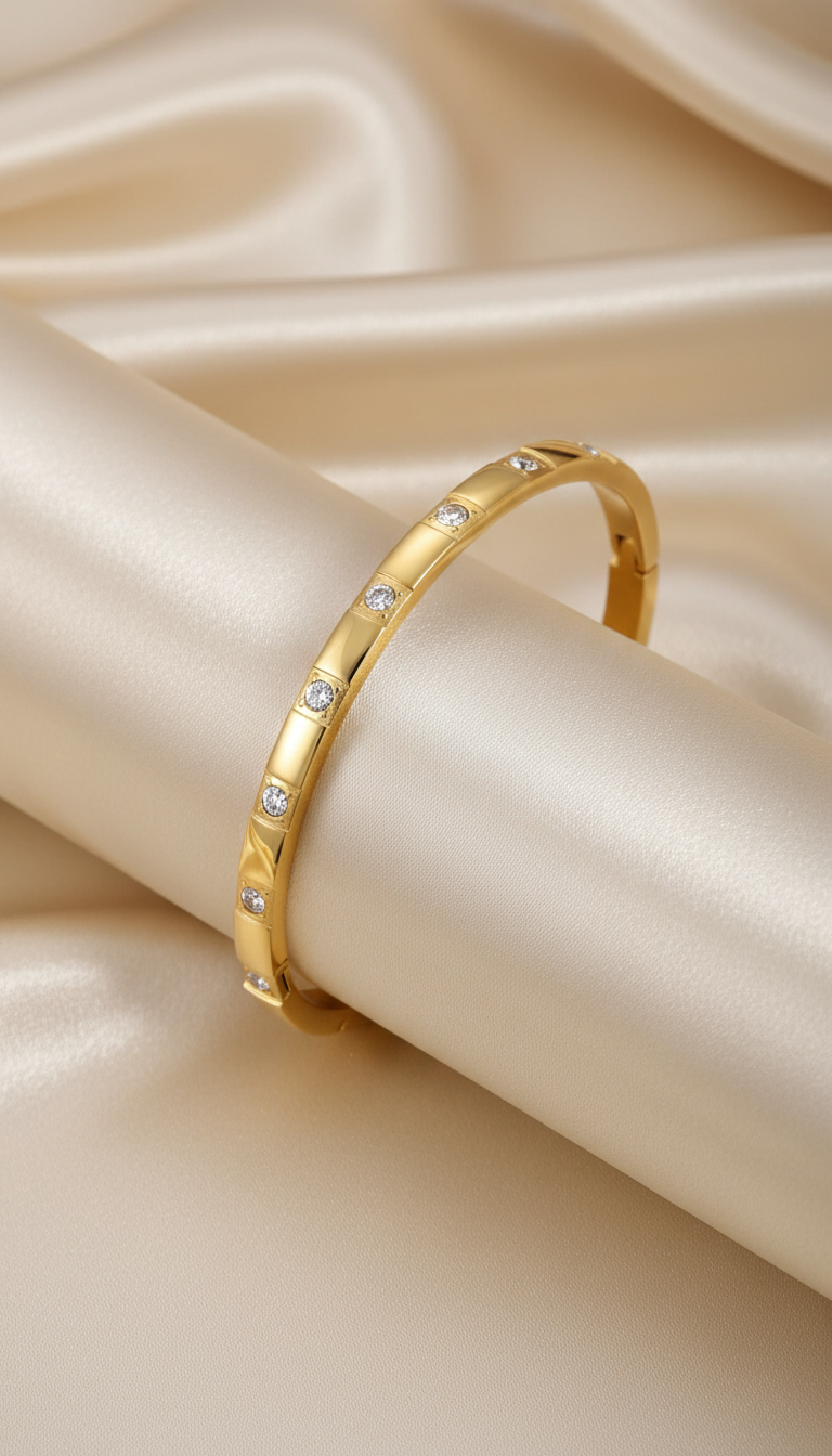Gold slim bangle bracelet with evenly spaced round cubic zirconia stones on satin background