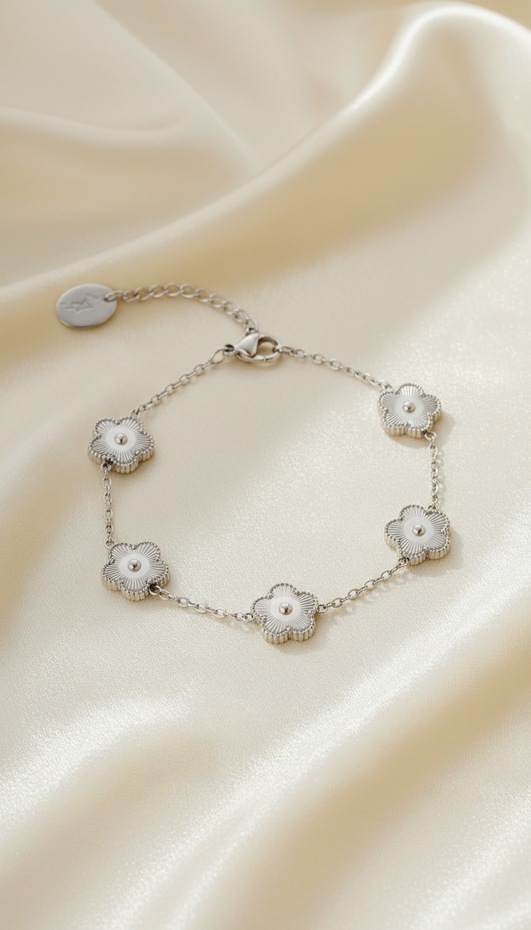 Silver bracelet with five textured floral charms on satin background